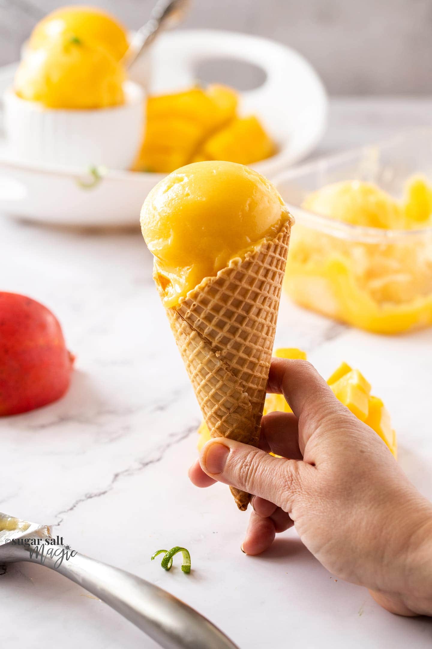 A waffle cone with a scoop of mango sorbet.