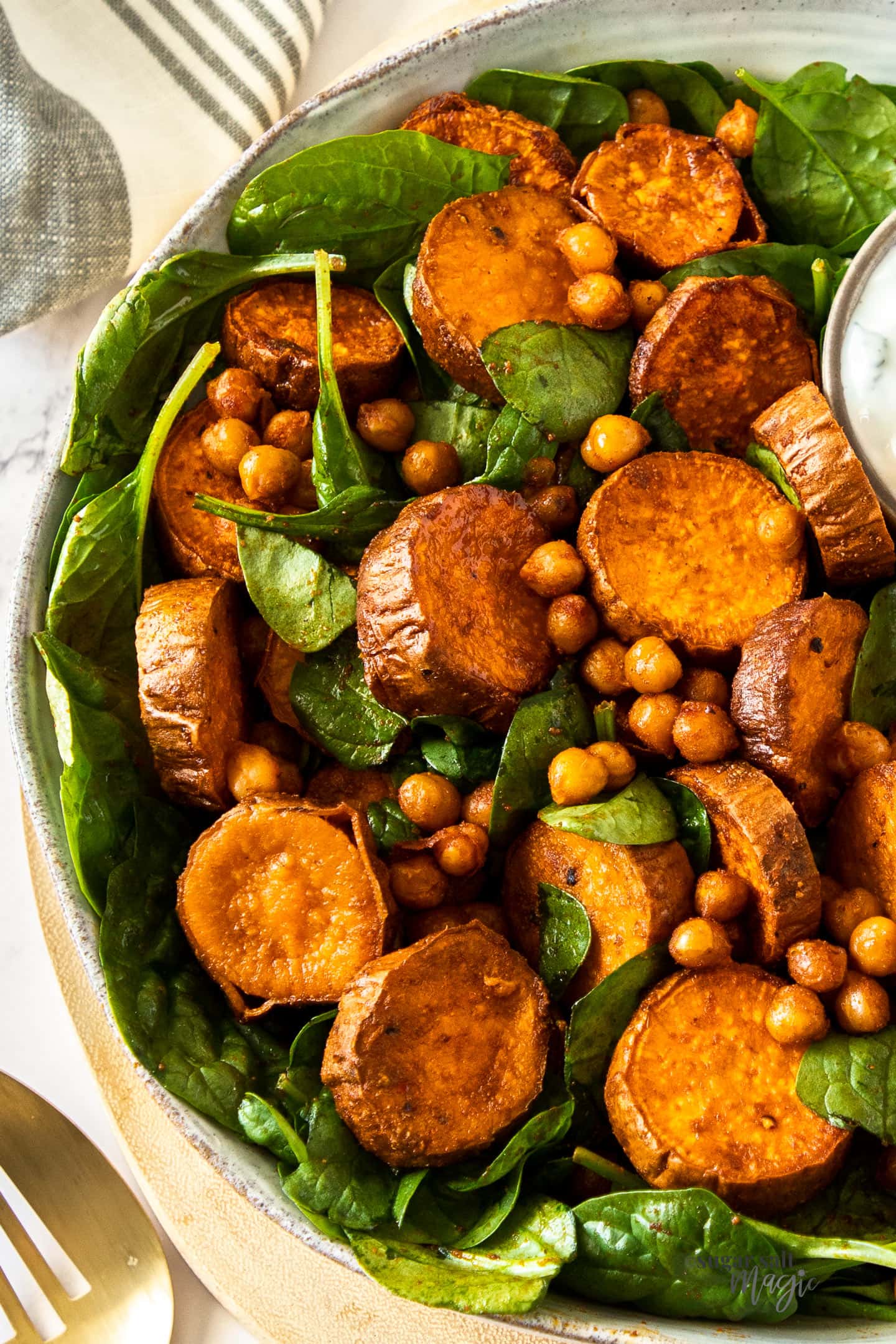 A white bowl filled with spinach and sweet potato on a wooden board
