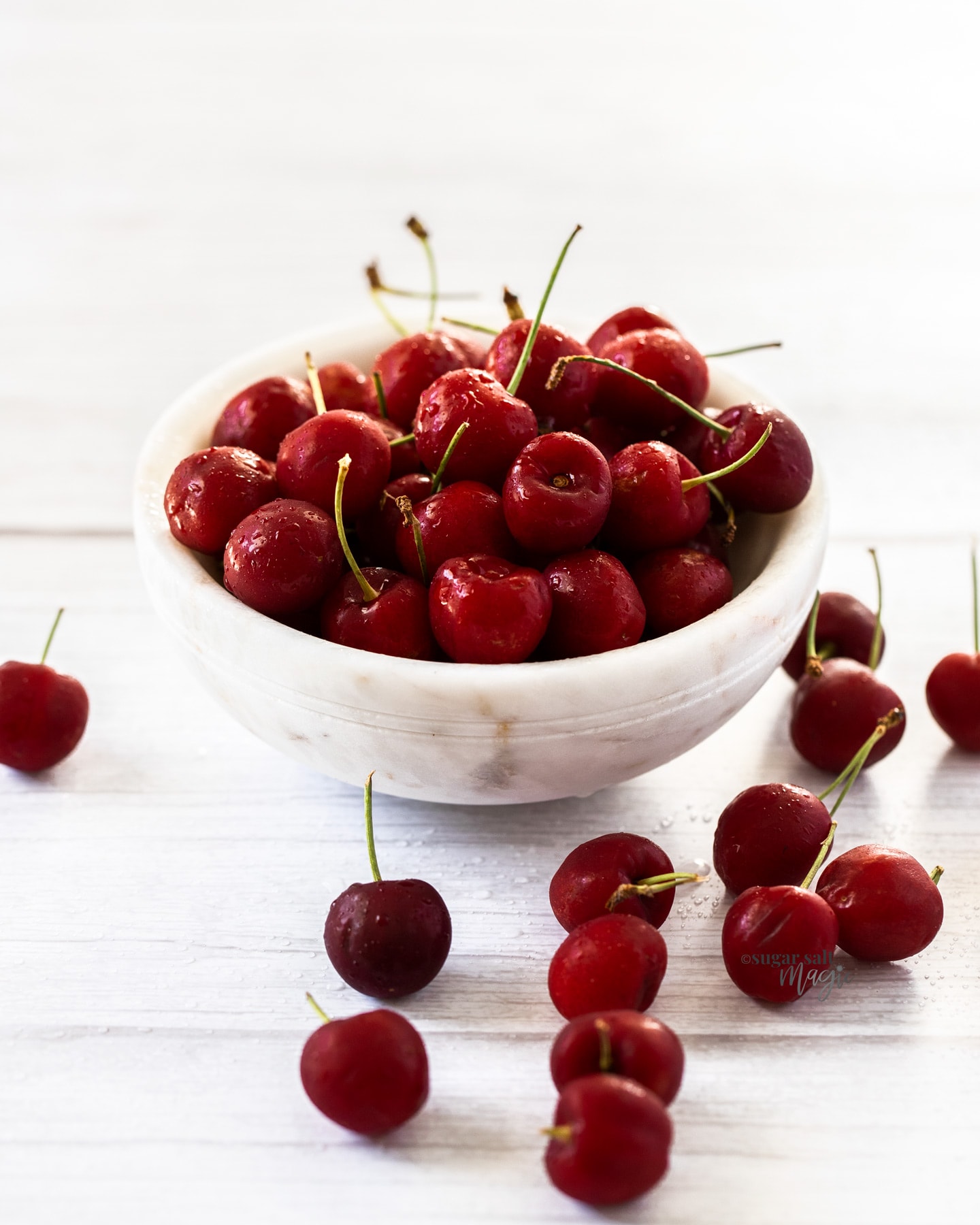 A white bowl filled with cherries