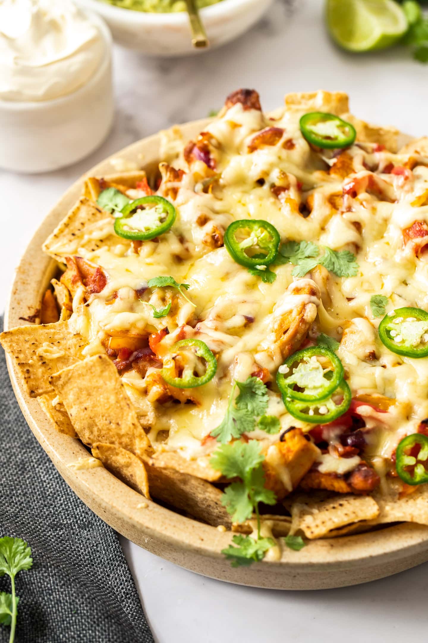 A baking dish filled with nachos and topped with sliced jalapenos.