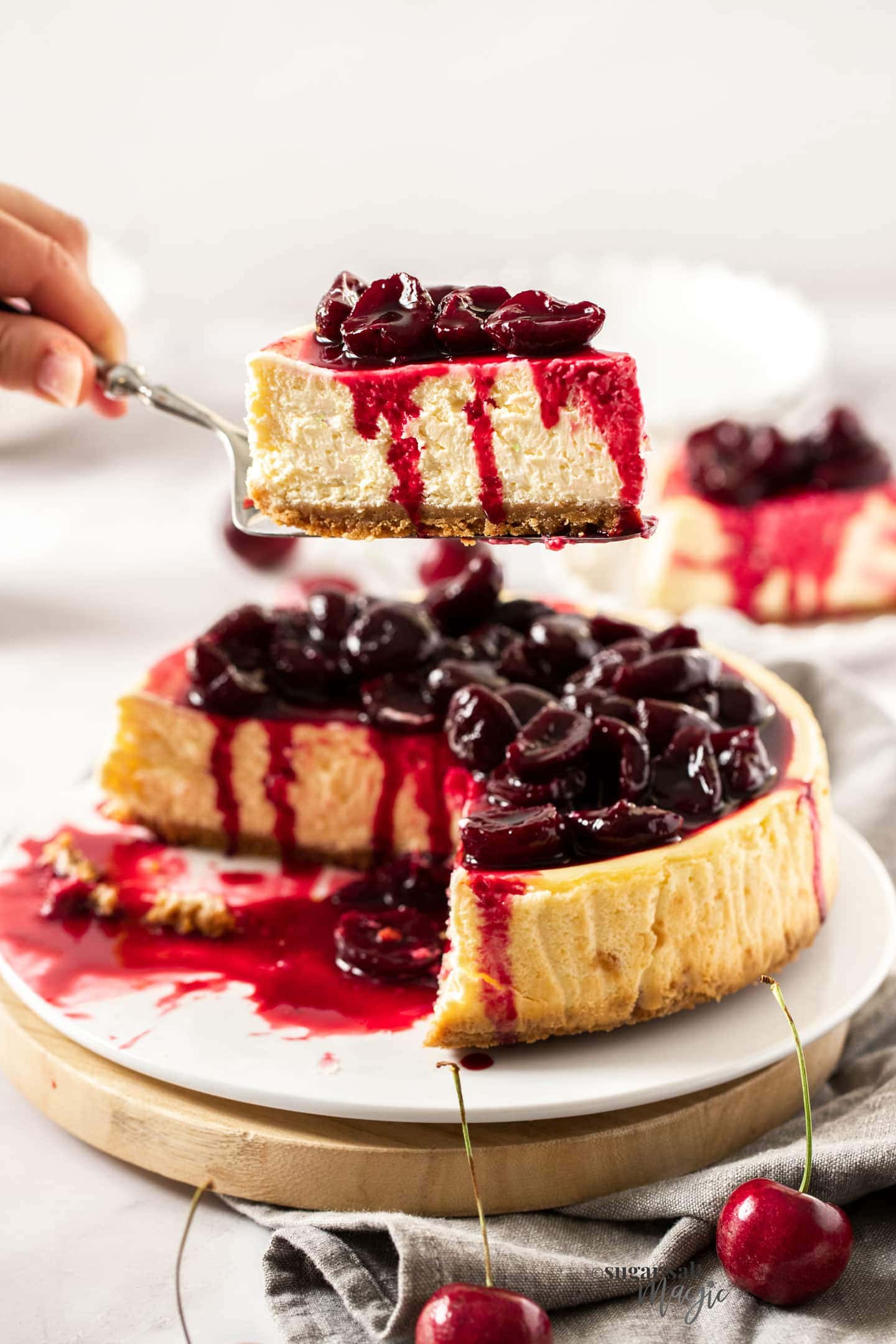 A slice of cherry cheesecake being held on a cake slice.