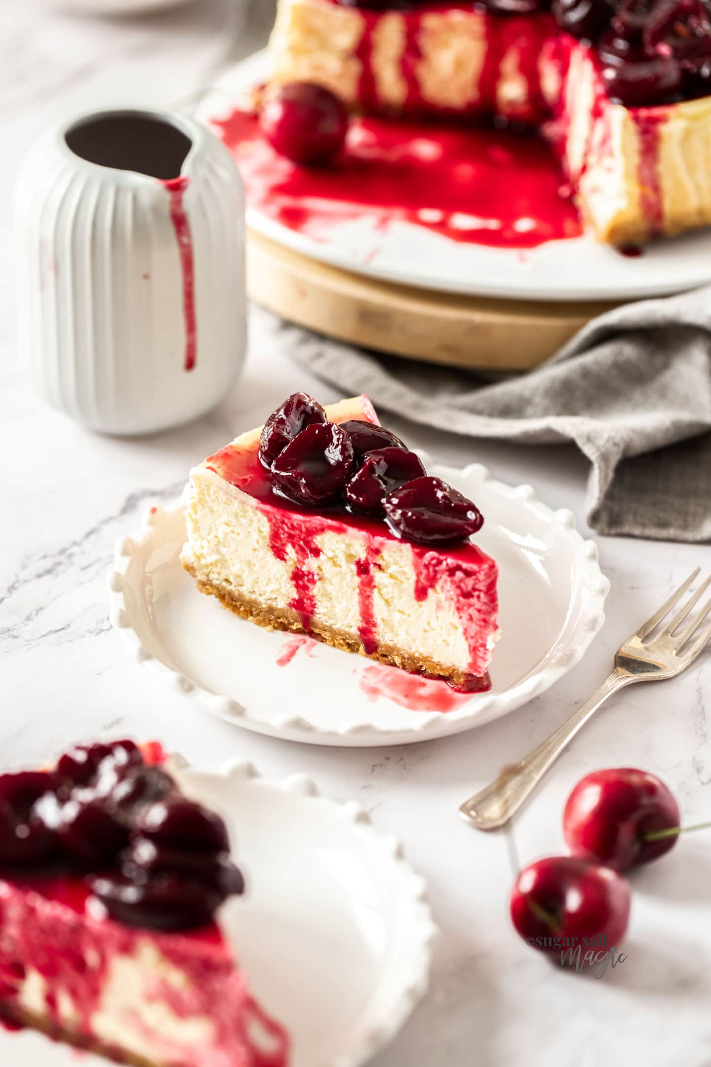 A slice of cherry cheesecake on a white plate with a fork next to it.