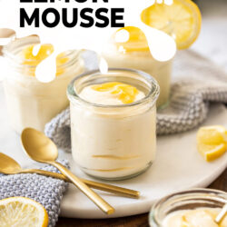 A glass filled with mousse and lemon curd with spoons in front