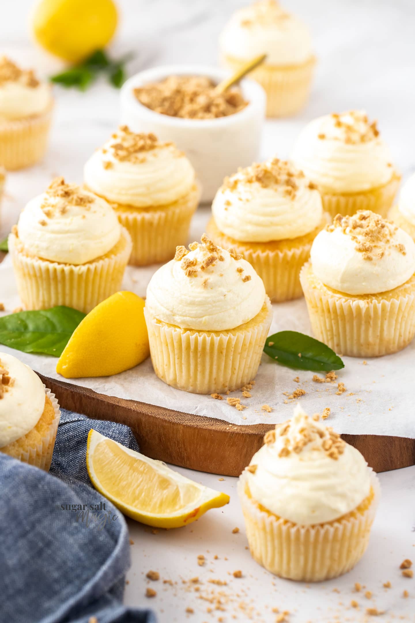 A batch of lemon cupcakes on a wooden board.