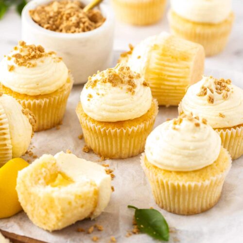 A batch of lemon cupcakes on a wooden board.