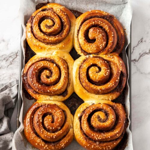 6 large cinnamon buns on a baking tray.