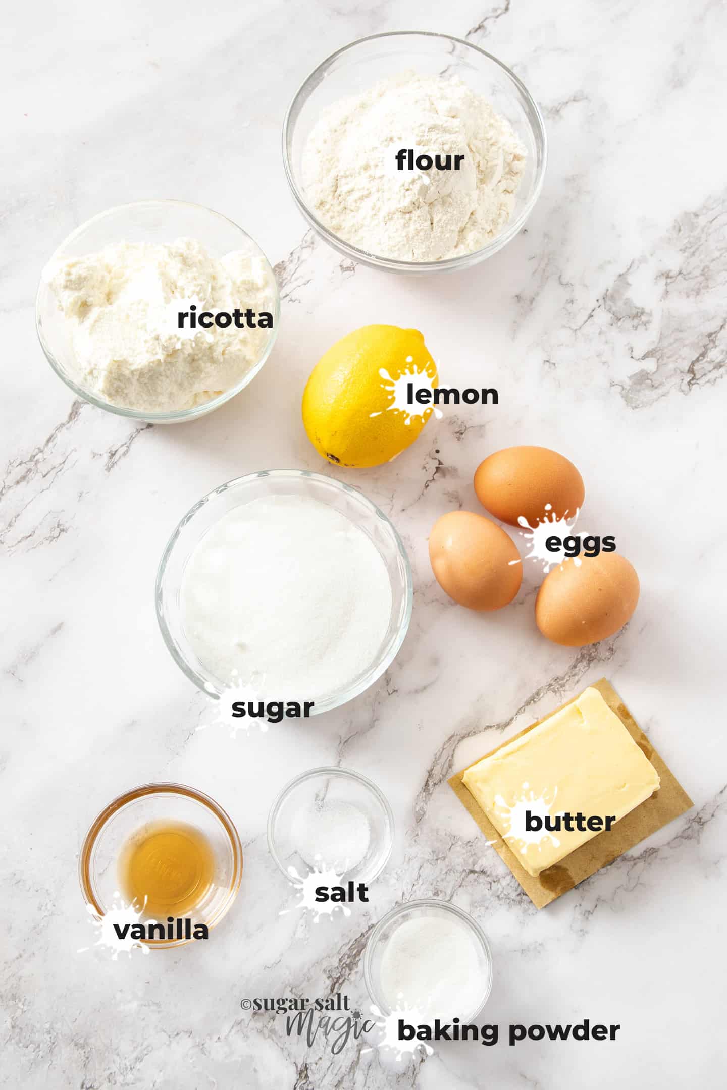 Ingredients for lemon ricotta cake on a white marble benchtop.