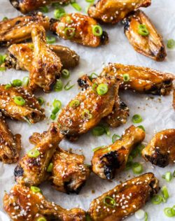 A batch of honey soy coated chicken wings on a sheet of baking paper.