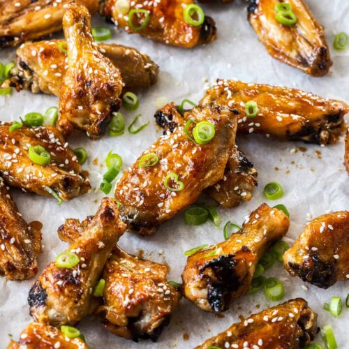 A batch of honey soy coated chicken wings on a sheet of baking paper.