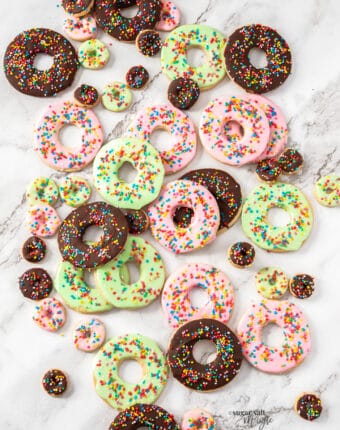 A batch of donut sugar cookies on a marble surface.