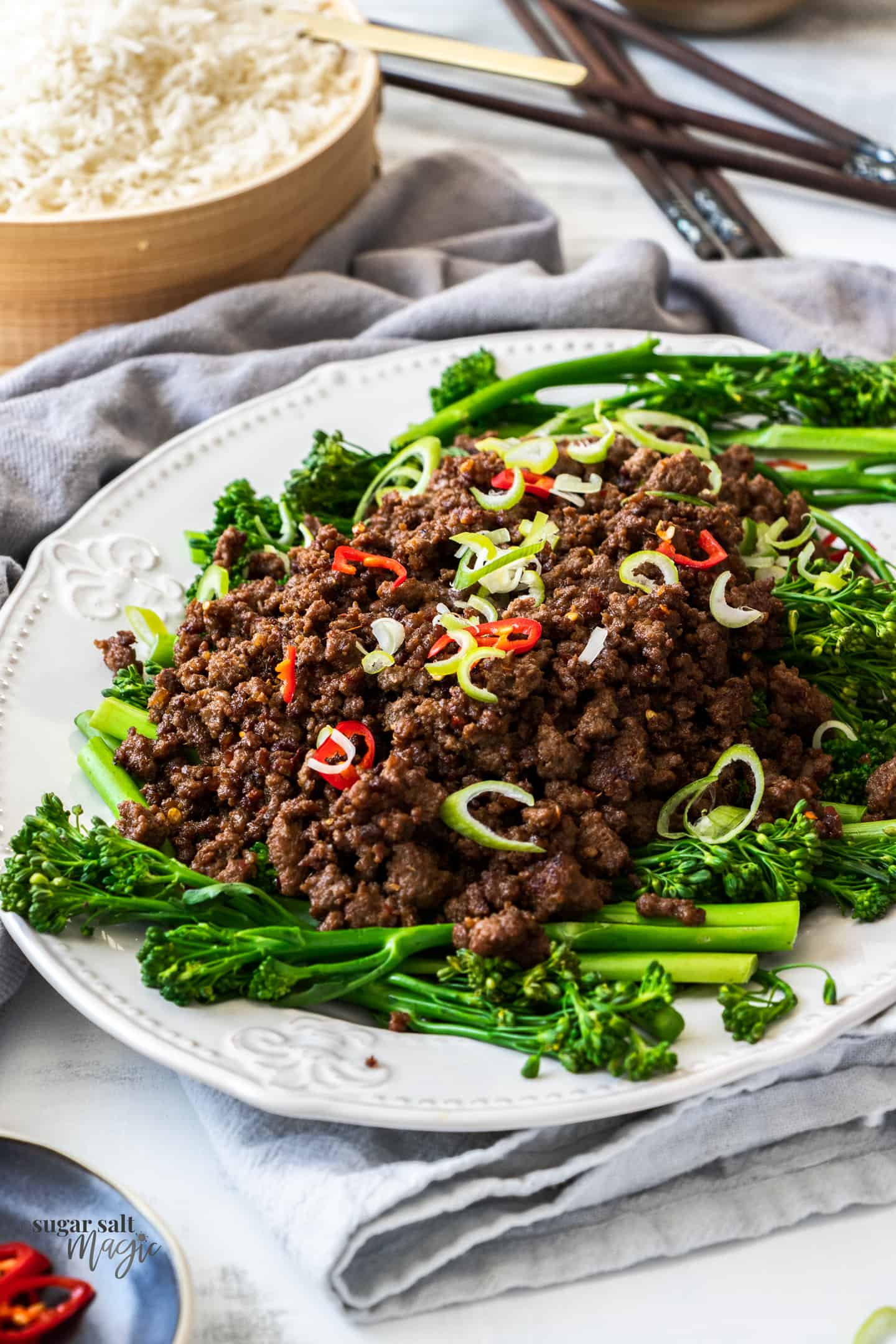A white plate topped with broccolini and cooked crispy beef mince.