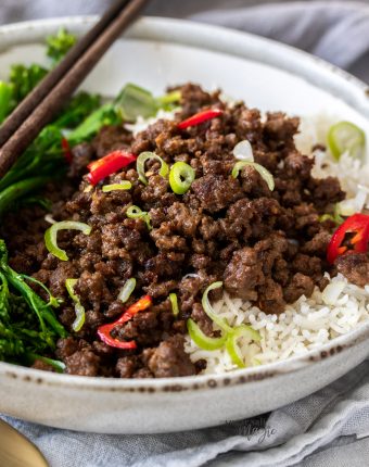 Closeup of a grey bowl filled with rice and crispy stir fried beef mince.
