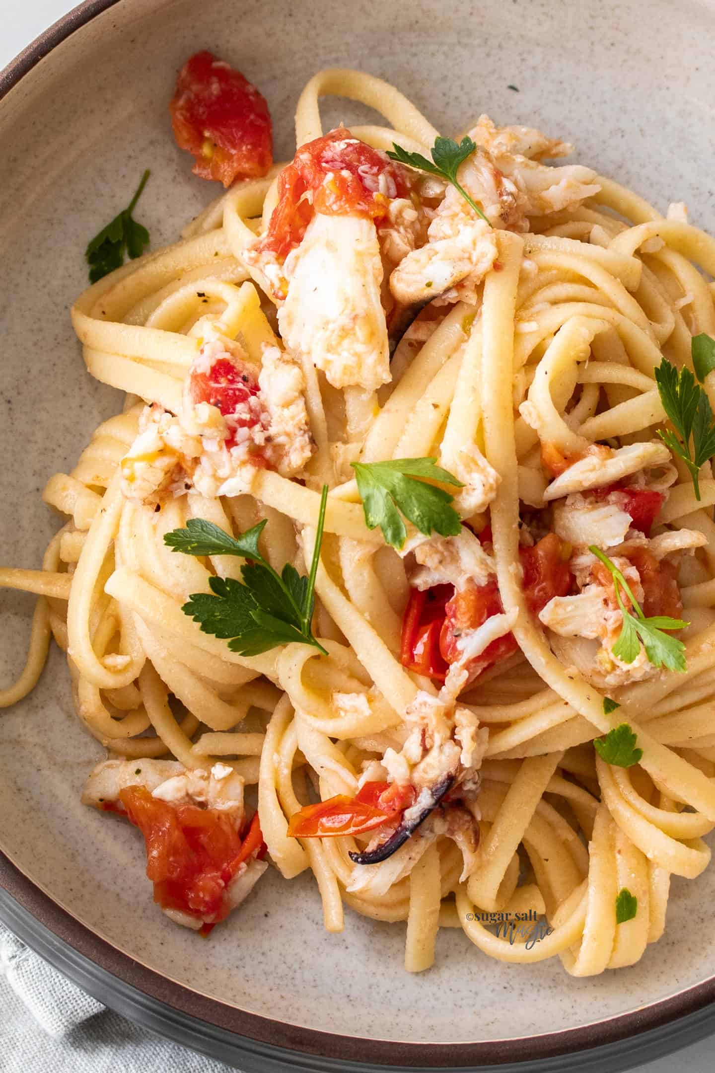 Closeup of tomato and crab linguine in a bowl.
