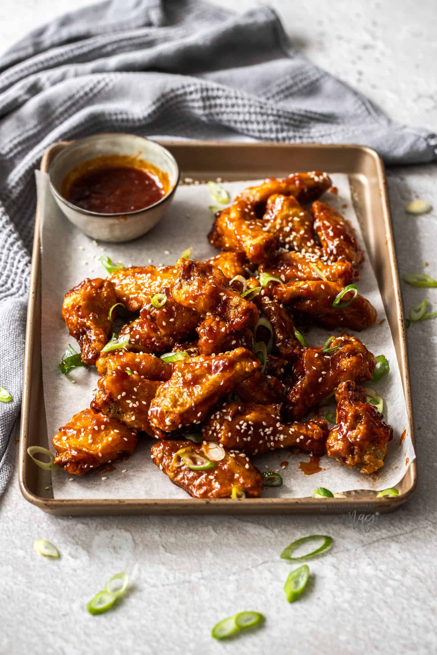 A of a pile of fried sticky chicken wings on a baking tray.