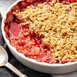 A white pie dish filled with baked strawberry crisp.