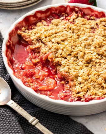 A white pie dish filled with baked strawberry crisp.