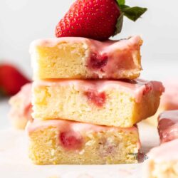 A stack of 3 strawberry blondies with a strawberry on top.