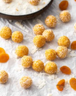 A batch of apricot bliss balls on a sheet of baking paper.