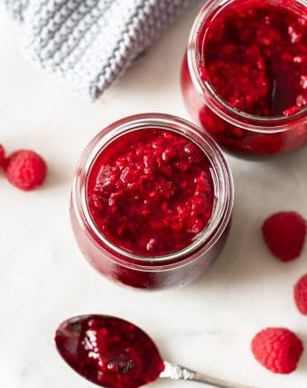 Top down view of homemade raspberry compote in a glass jar.