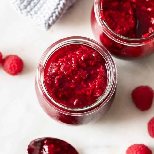 Top down view of homemade raspberry compote in a glass jar.