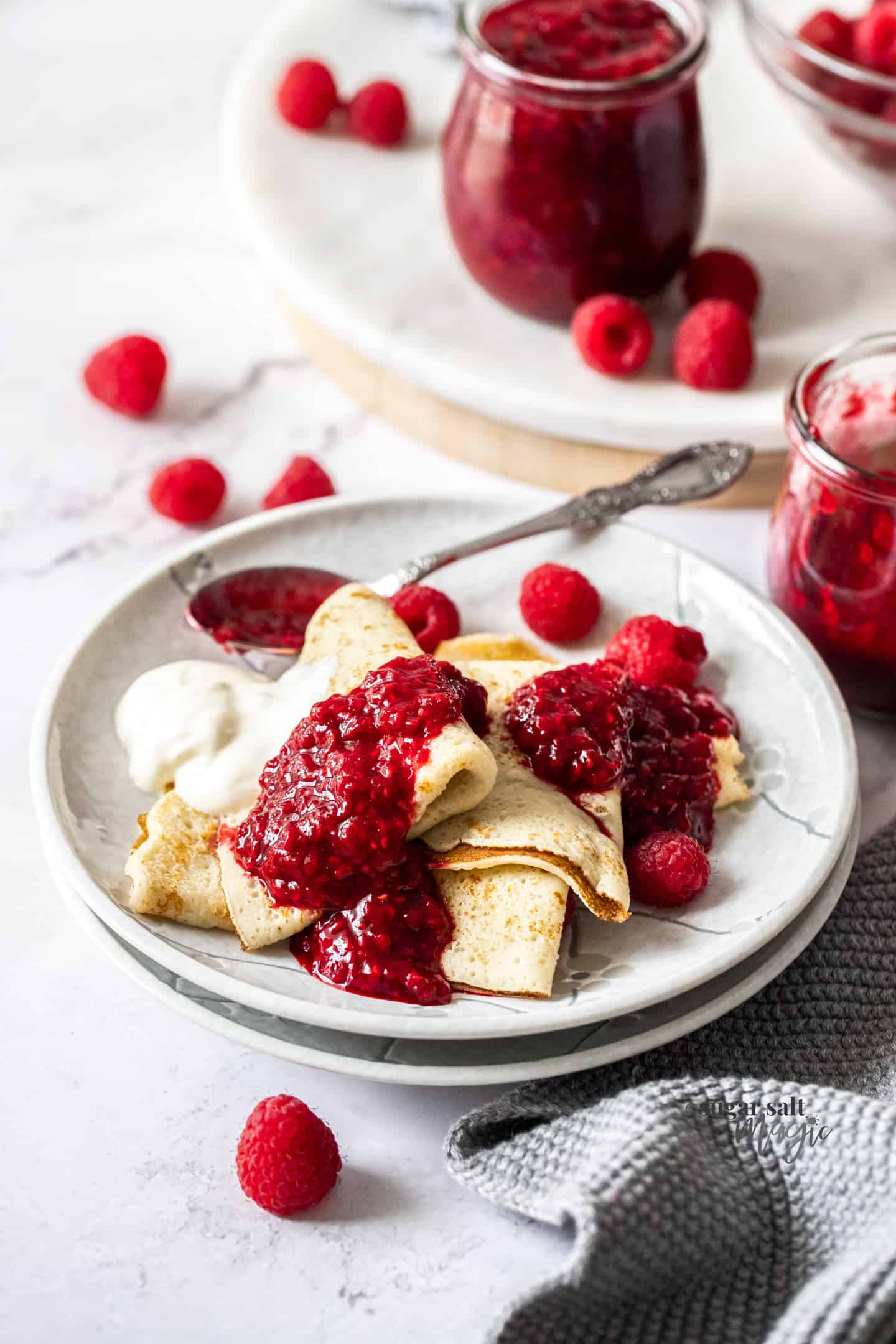Pancakes on a white plate topped with raspberry compote.
