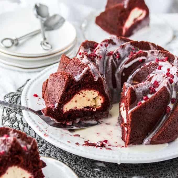 A red velvet bundt cake on a white cake plate.