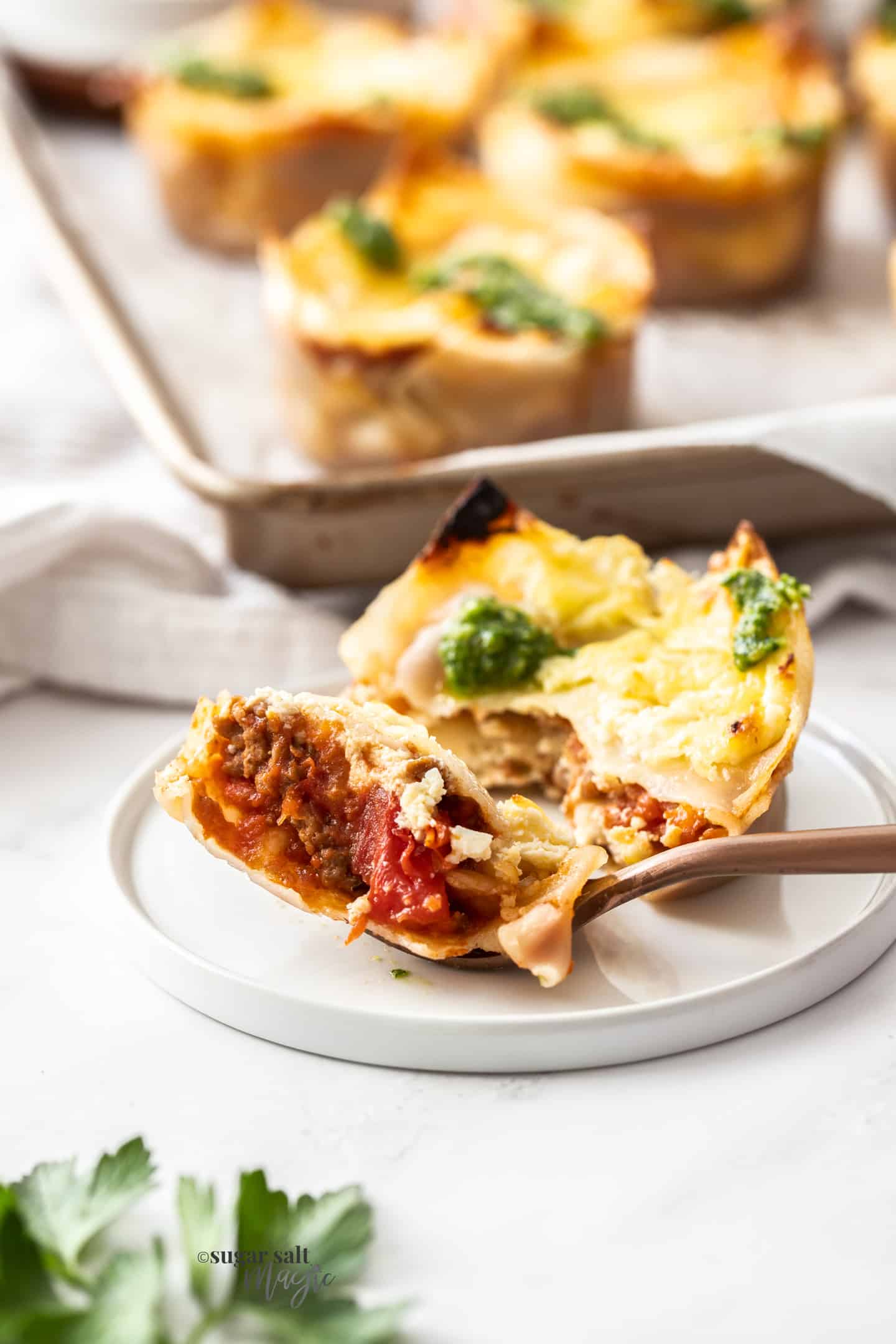 A lasagna cupcake on a small plate with a fork ful cut away.