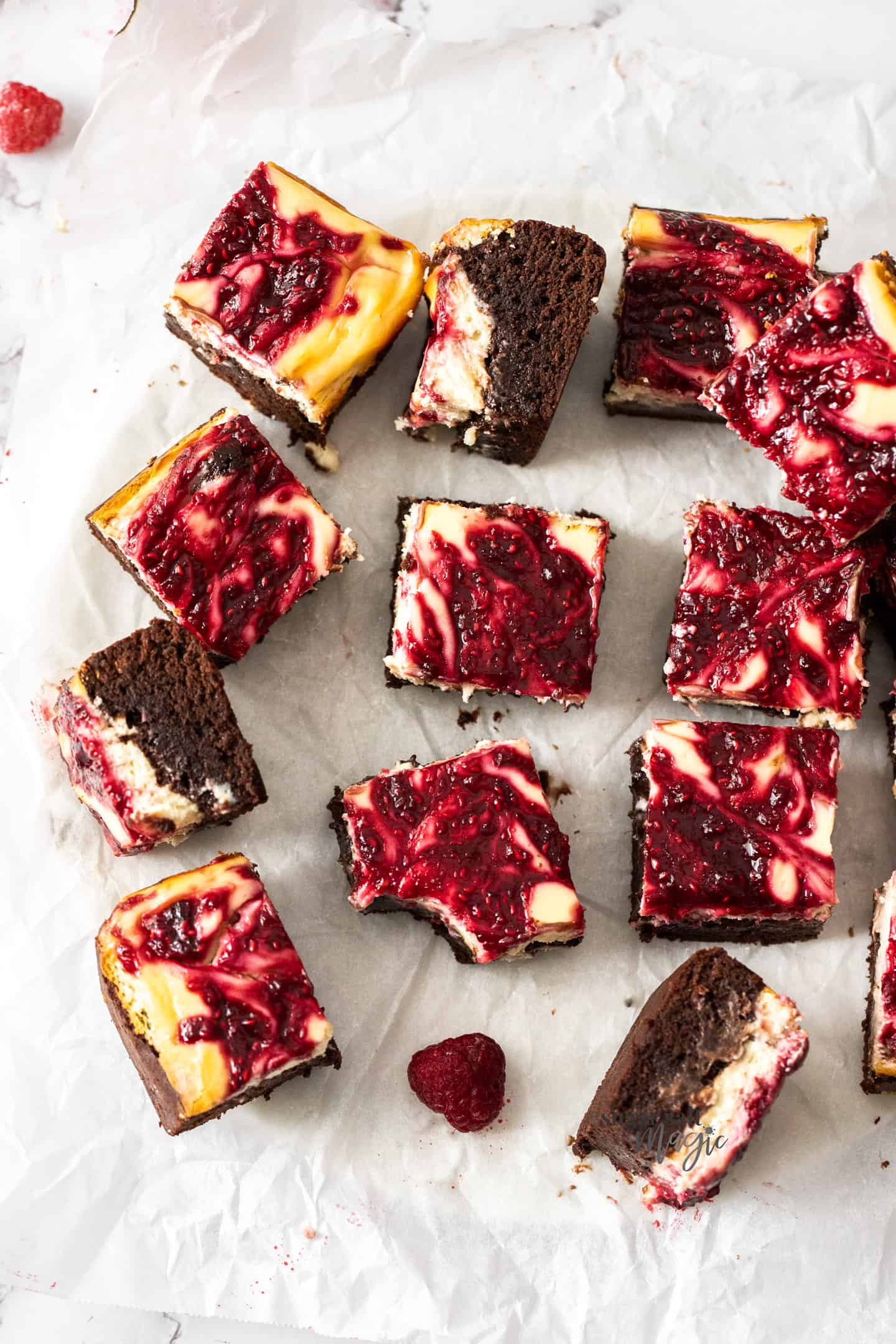 A batch of raspberry cheesecake brownies on a sheet of baking paper.