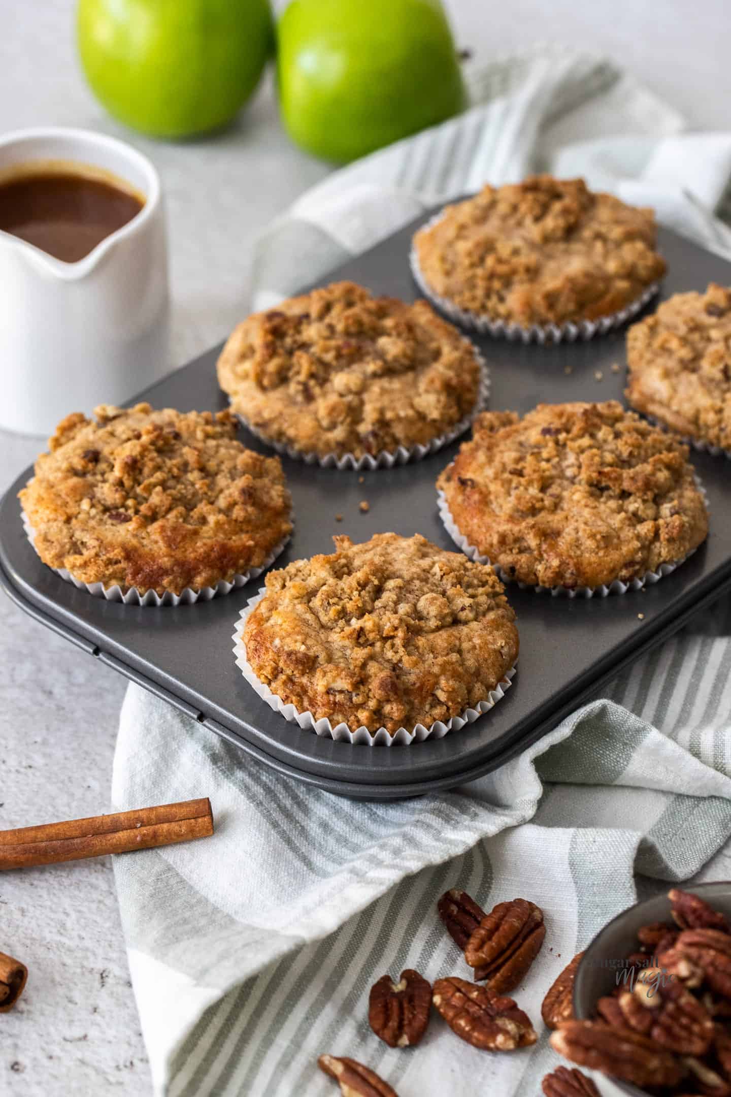 A muffin tin with 6 crumble-topped muffins in it.