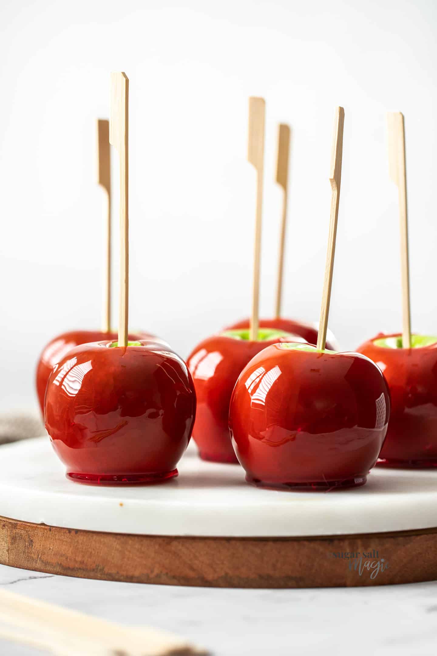 Close up of red toffee apples sitting on a marble platter.