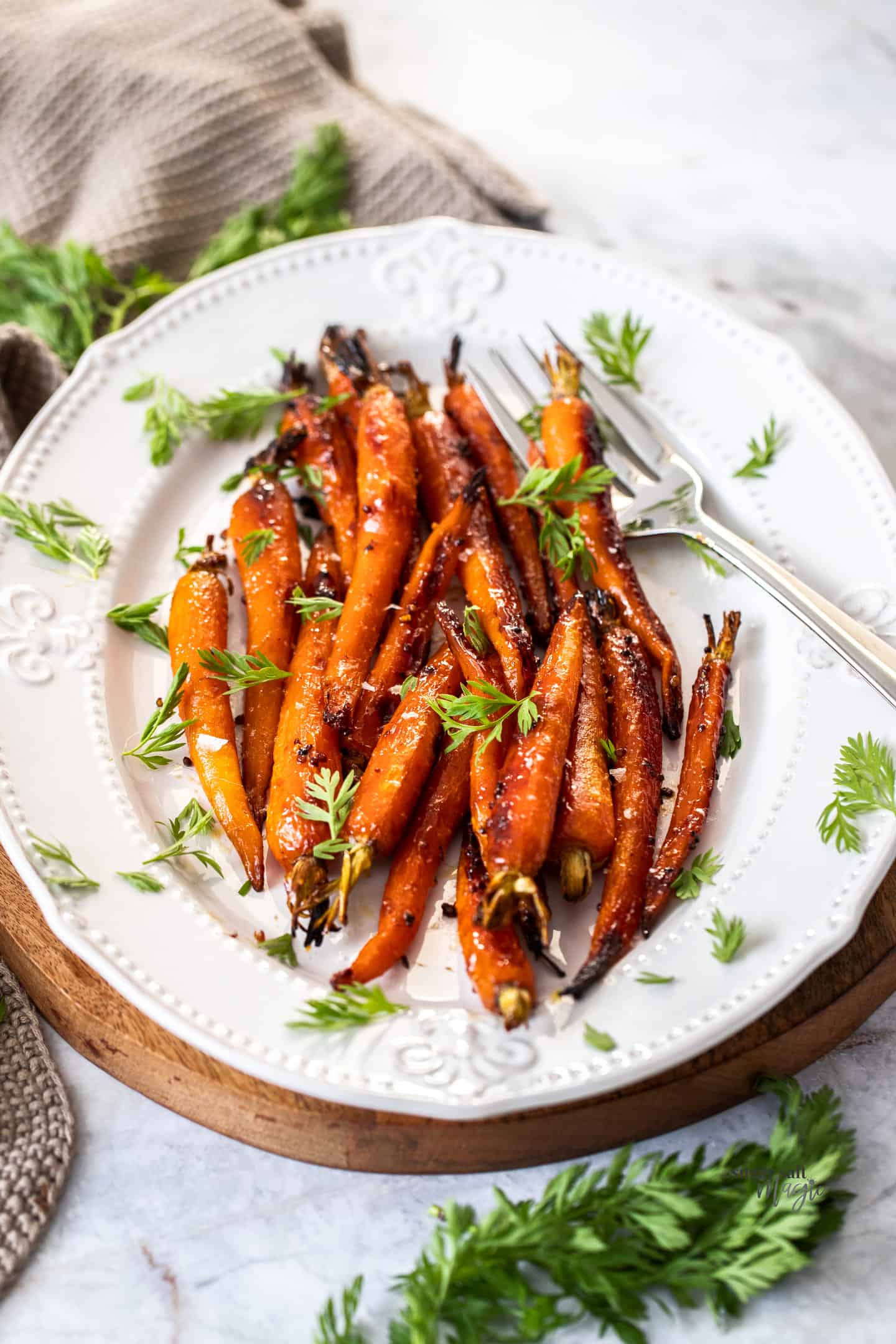 A batch of roasted baby carrots on a white platter.