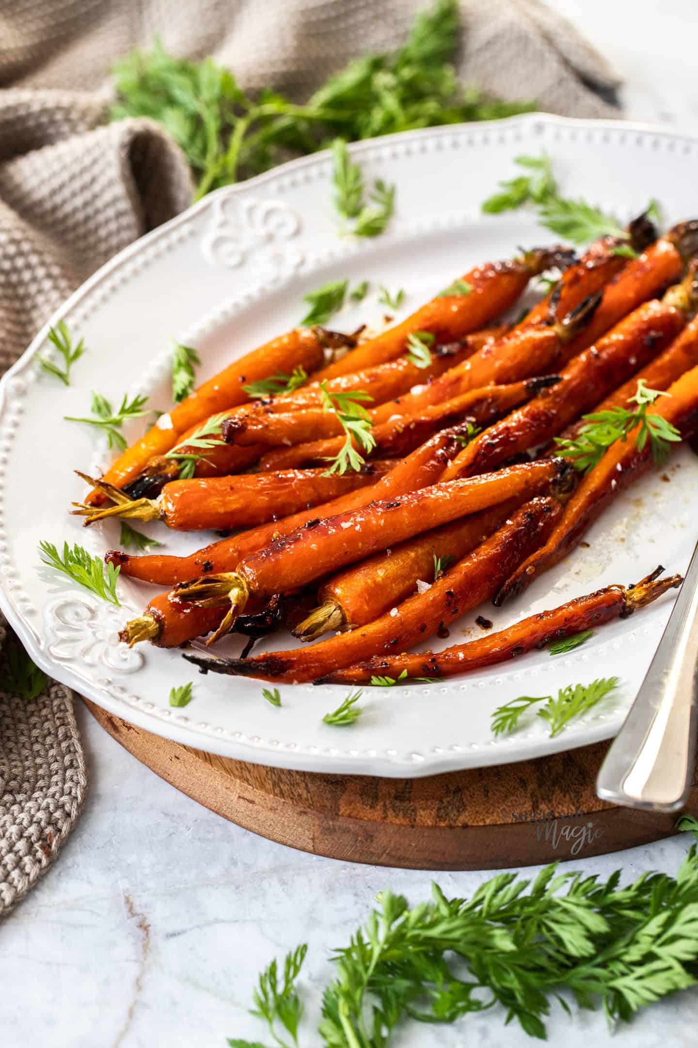 A batch of roasted baby carrots on a white and wooden platter.