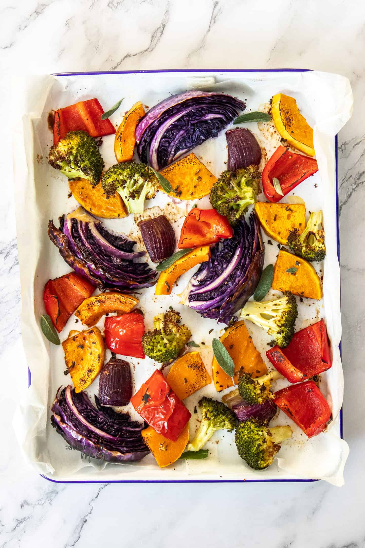 Top down view of a sheet pan filled with colourful roasted vegetables.