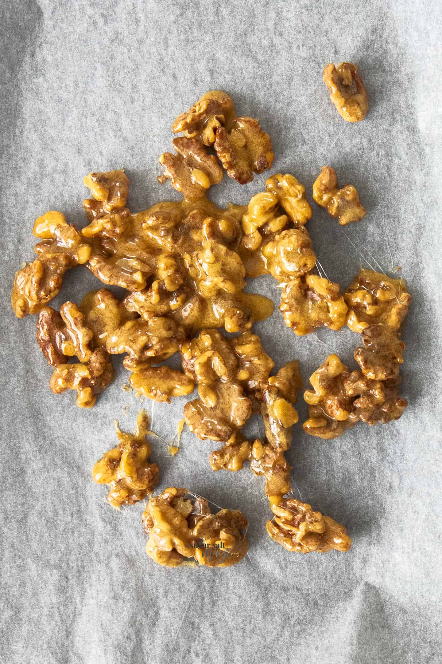 A batch of candied walnuts on a sheet of baking paper.