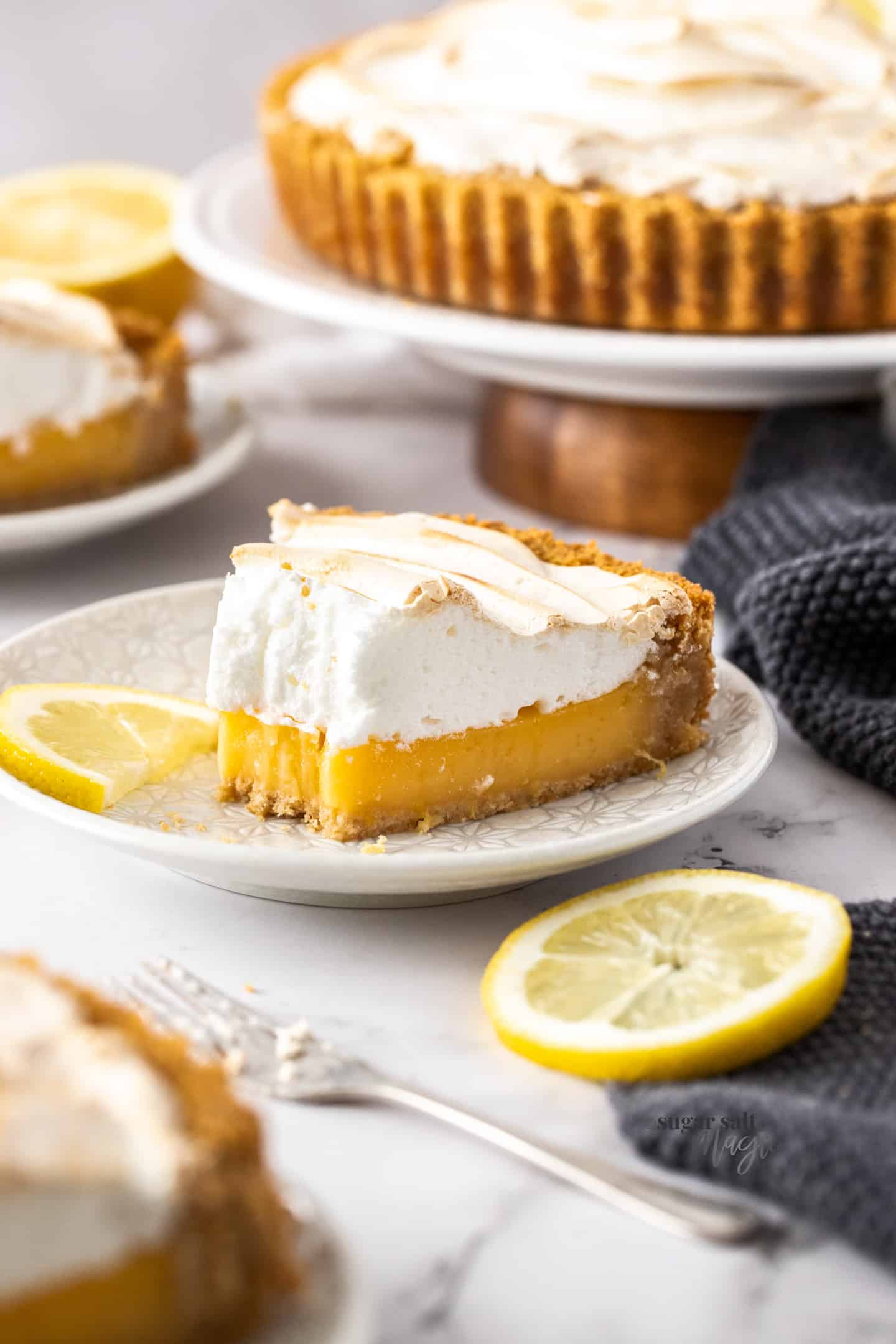 A slice of lemon meringue pie on a white plate with a forkful taken out of it.