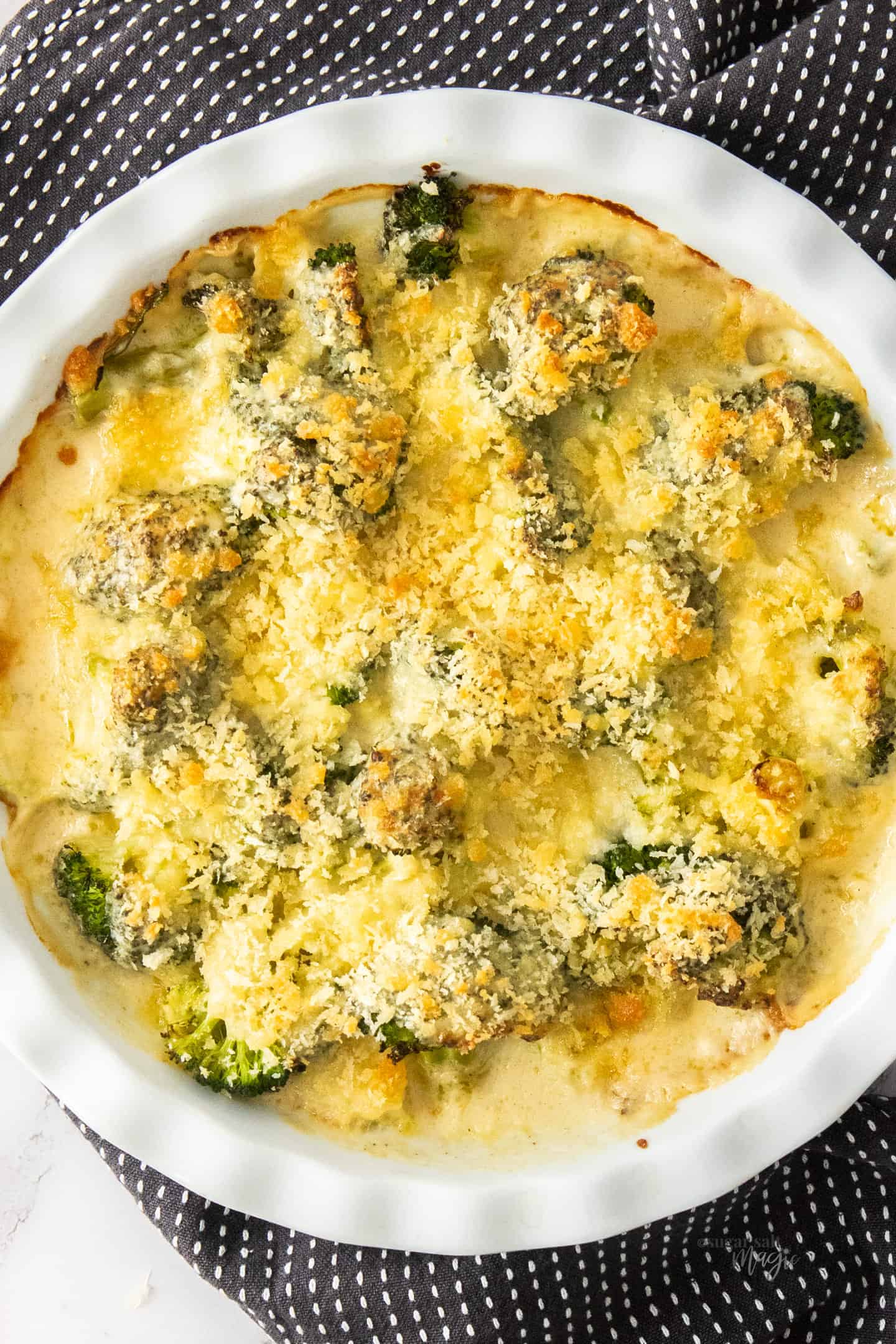 A white pie dish filled with broccoli cheese casserole.