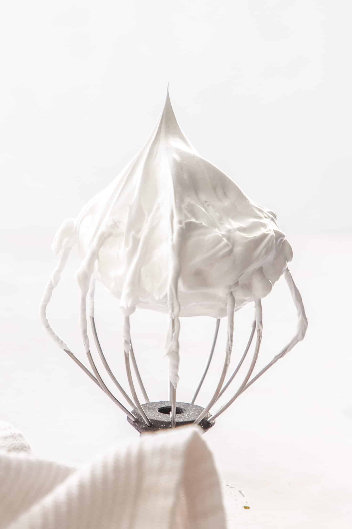 A whisk with a peak of meringue on it.