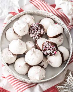 A pile of peppermint meringues in a small white tin.