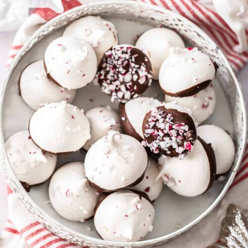 A pile of peppermint meringues in a small white tin.