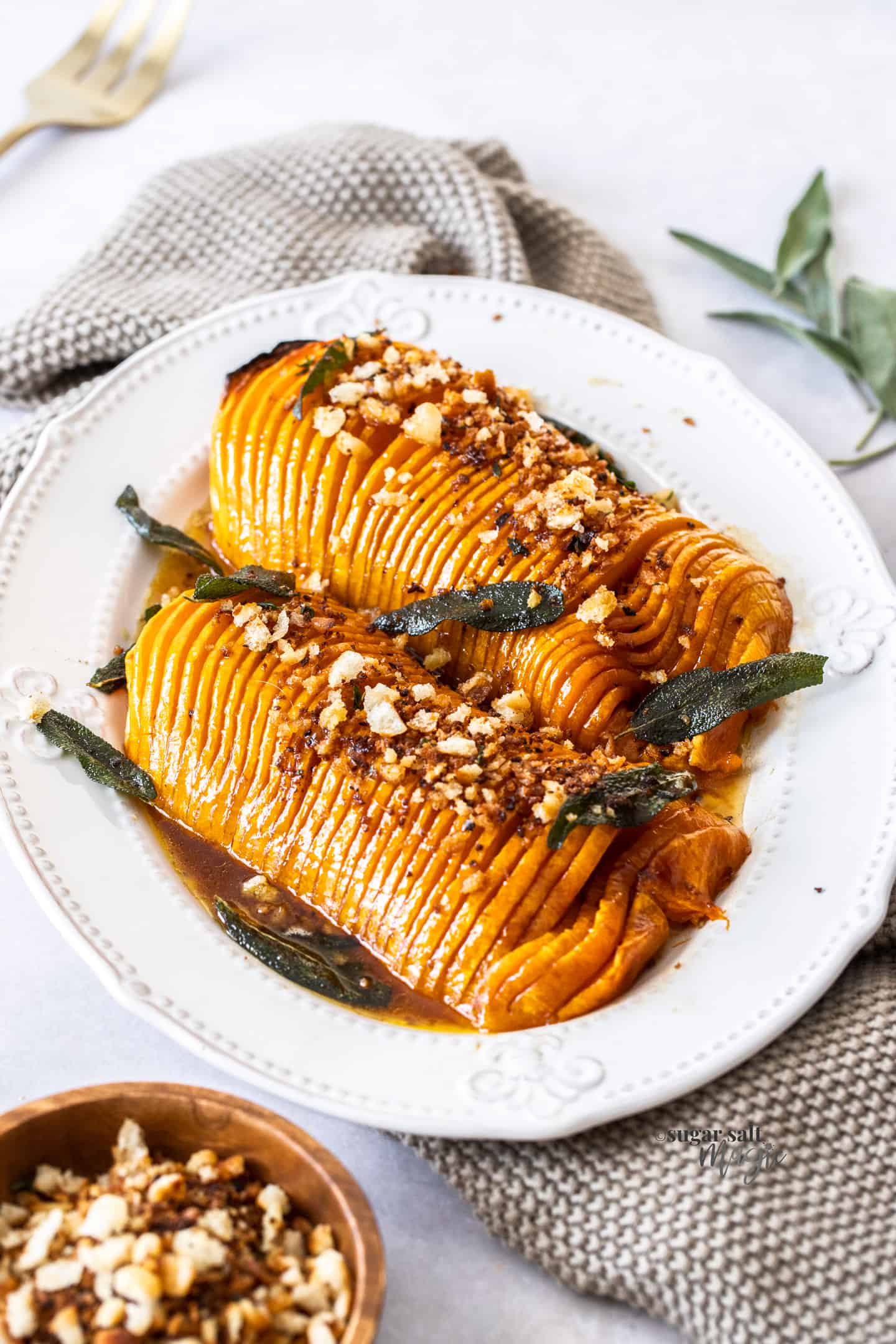 Two pieces of roasted hasselback butternut squahs on a white platter.
