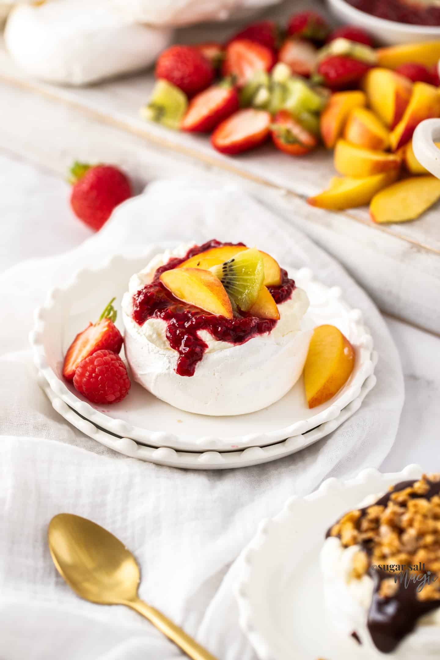 A mini pavlova topped with fruit on a small dessert plate.