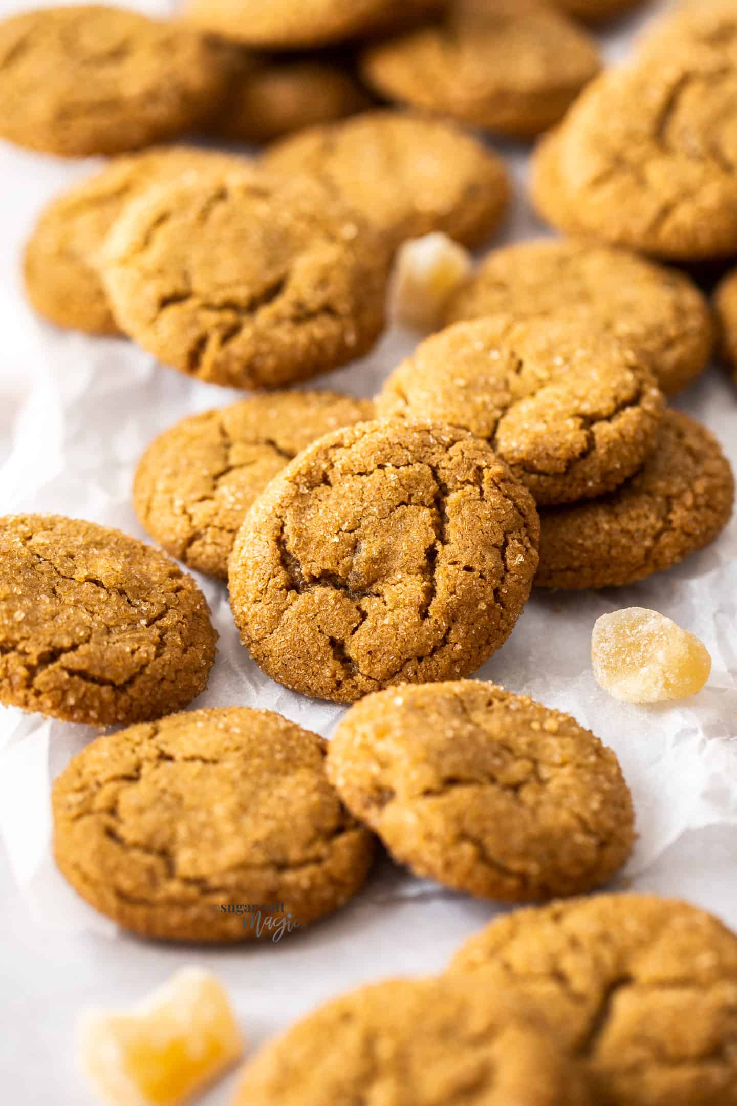 A pile of ginger cookies with pieces of crystallised ginger around.