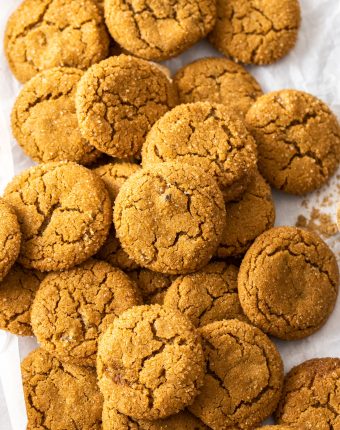 A pile of ginger cookies on a sheet of baking paper.