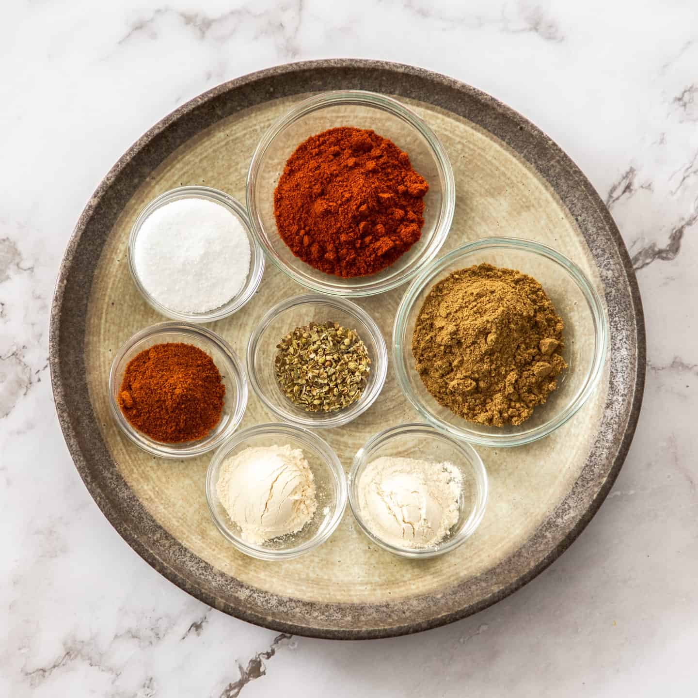 Ingredients for taco seasoning on a round plate.