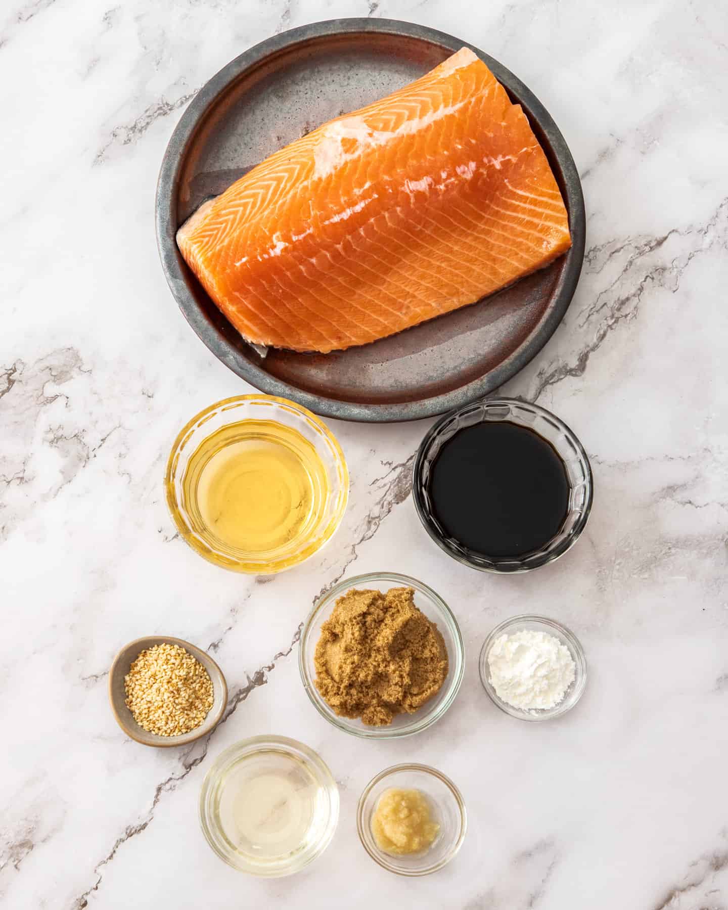 Ingredients for baked teriyaki salmon on a marble benchtop.