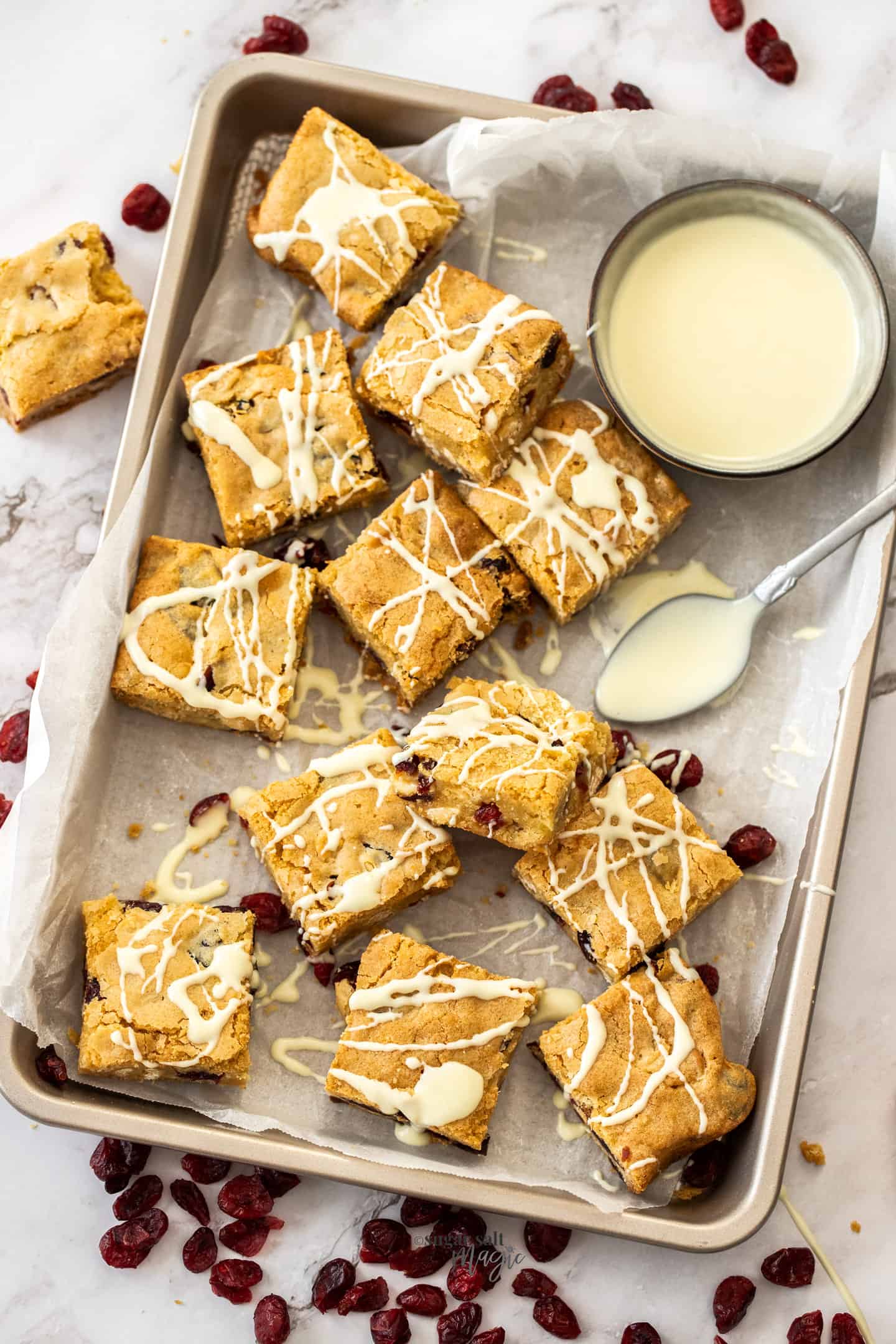 Top down view of a batch of blondies drizzled with white chocolate.