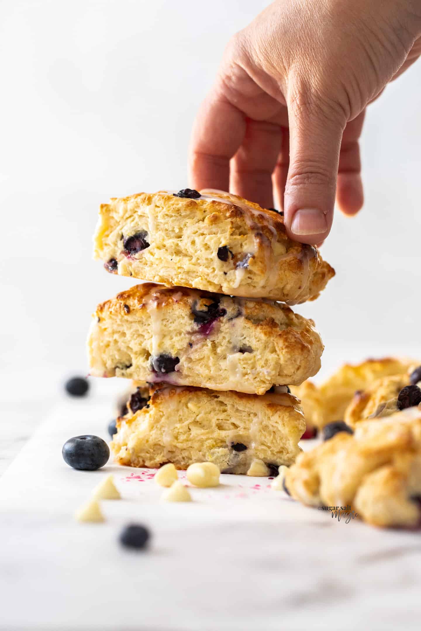A stack of 3 scones with a hand grabbing the one on top.