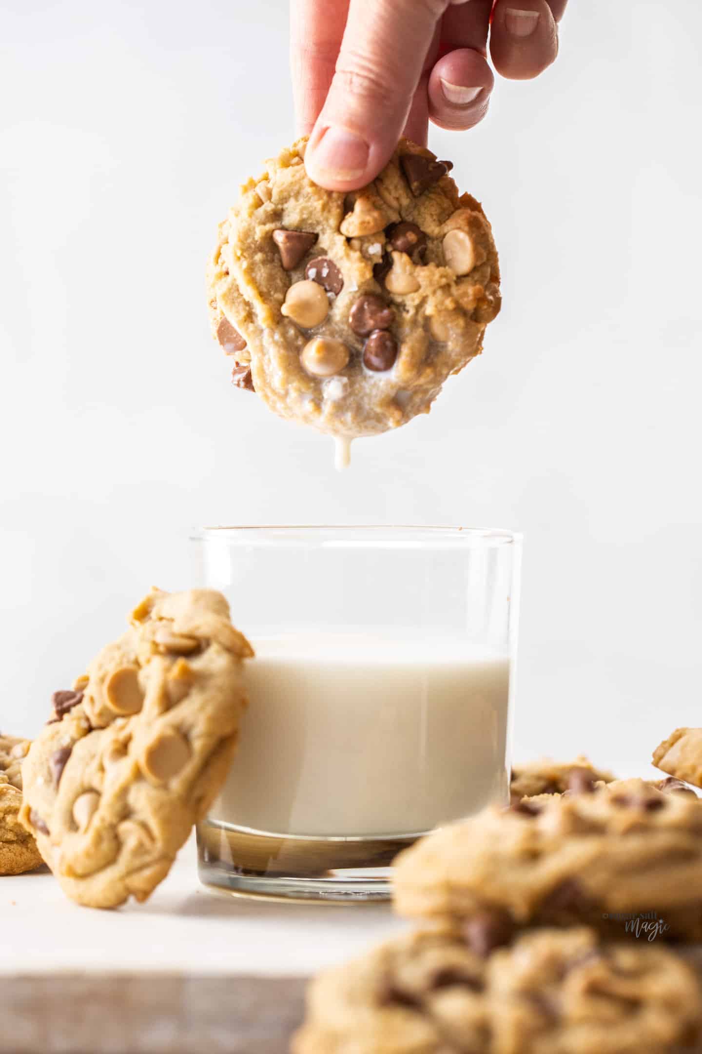 A caramilk cookie being dunked into a glass of milk.