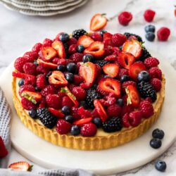 A tart filled with custard and topped with fresh berries.