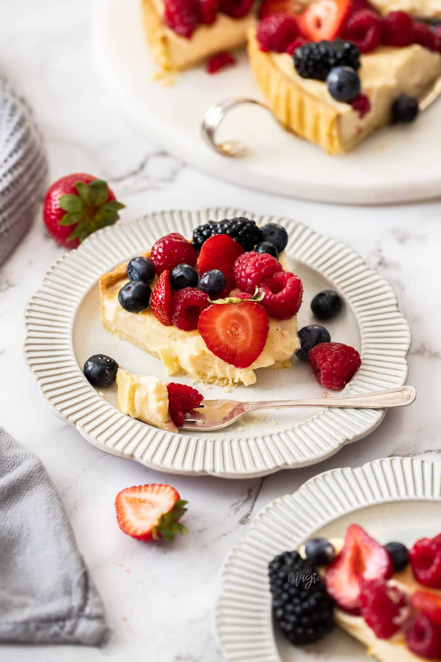 A slice of tart on a plate with a forkful sitting just to the side.